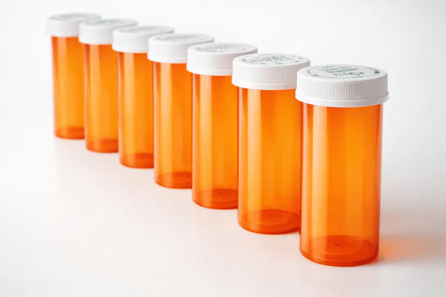 Orange pharmacy vials with white child-resistant caps arranged in a row.
